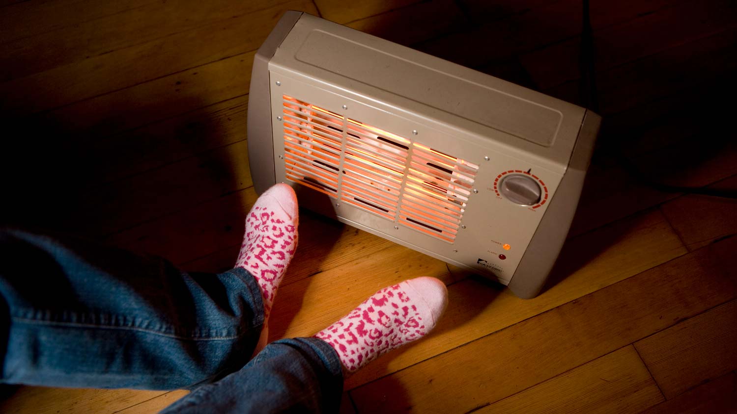 A person warming her feet in front of a space heater