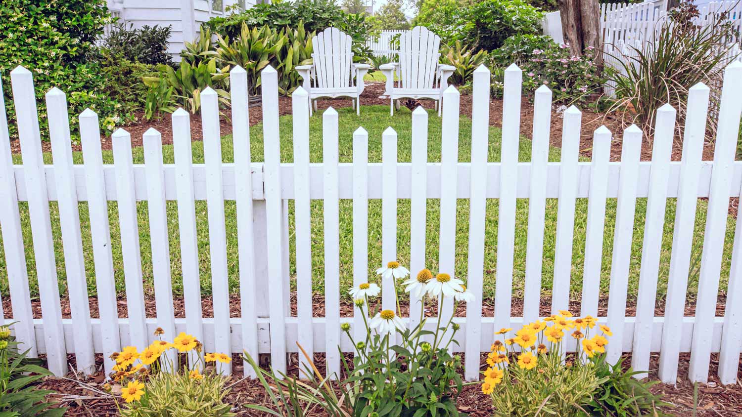 White picket fence in residential neighborhood with grass lawn