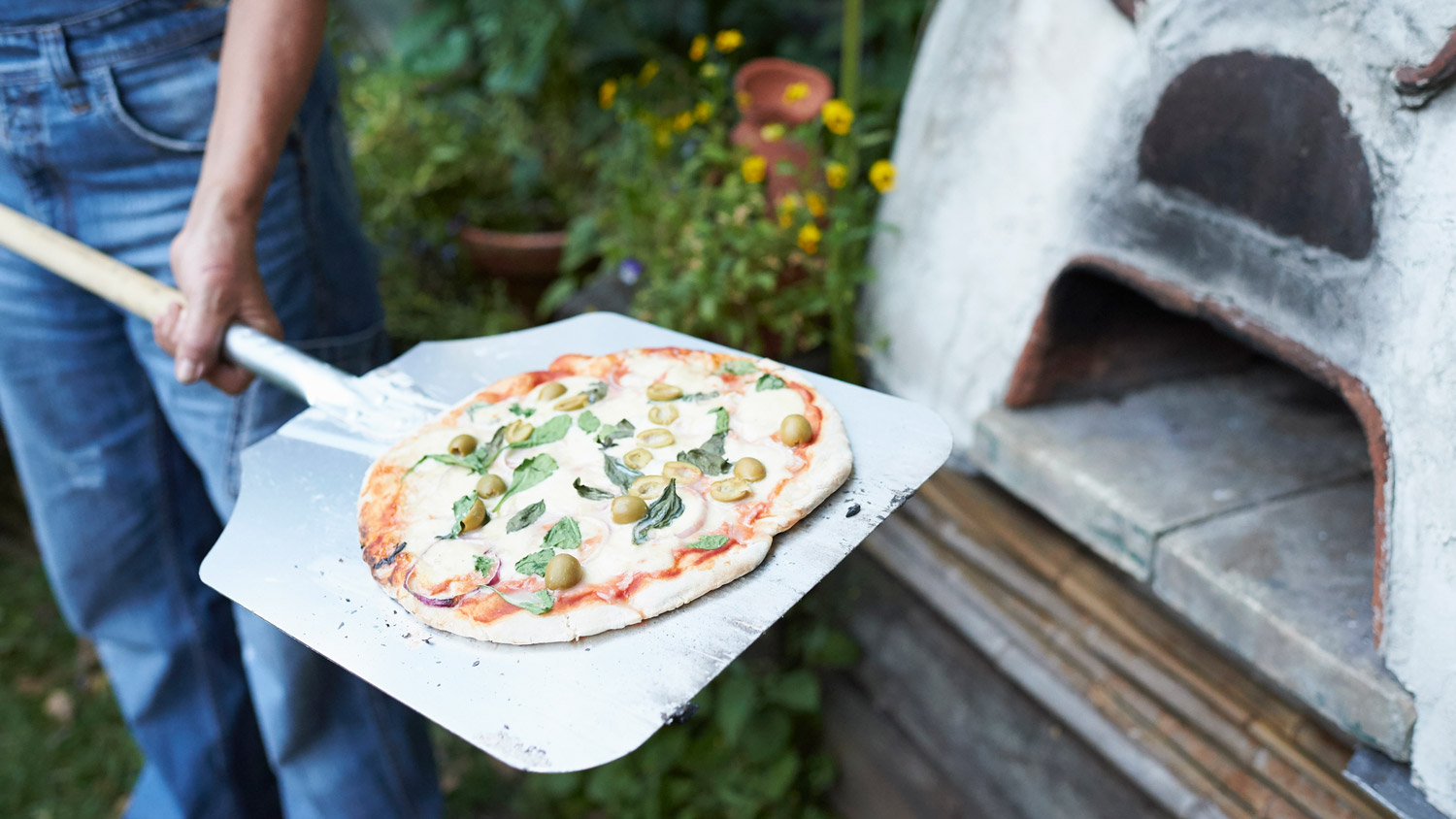 Pizza coming out of a backyard pizza oven