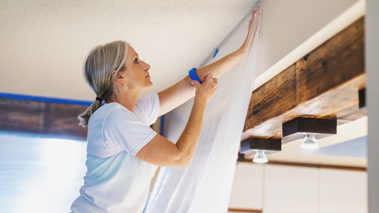 Adult Female Using Painter's Tape and Plastic for Painting Preparation