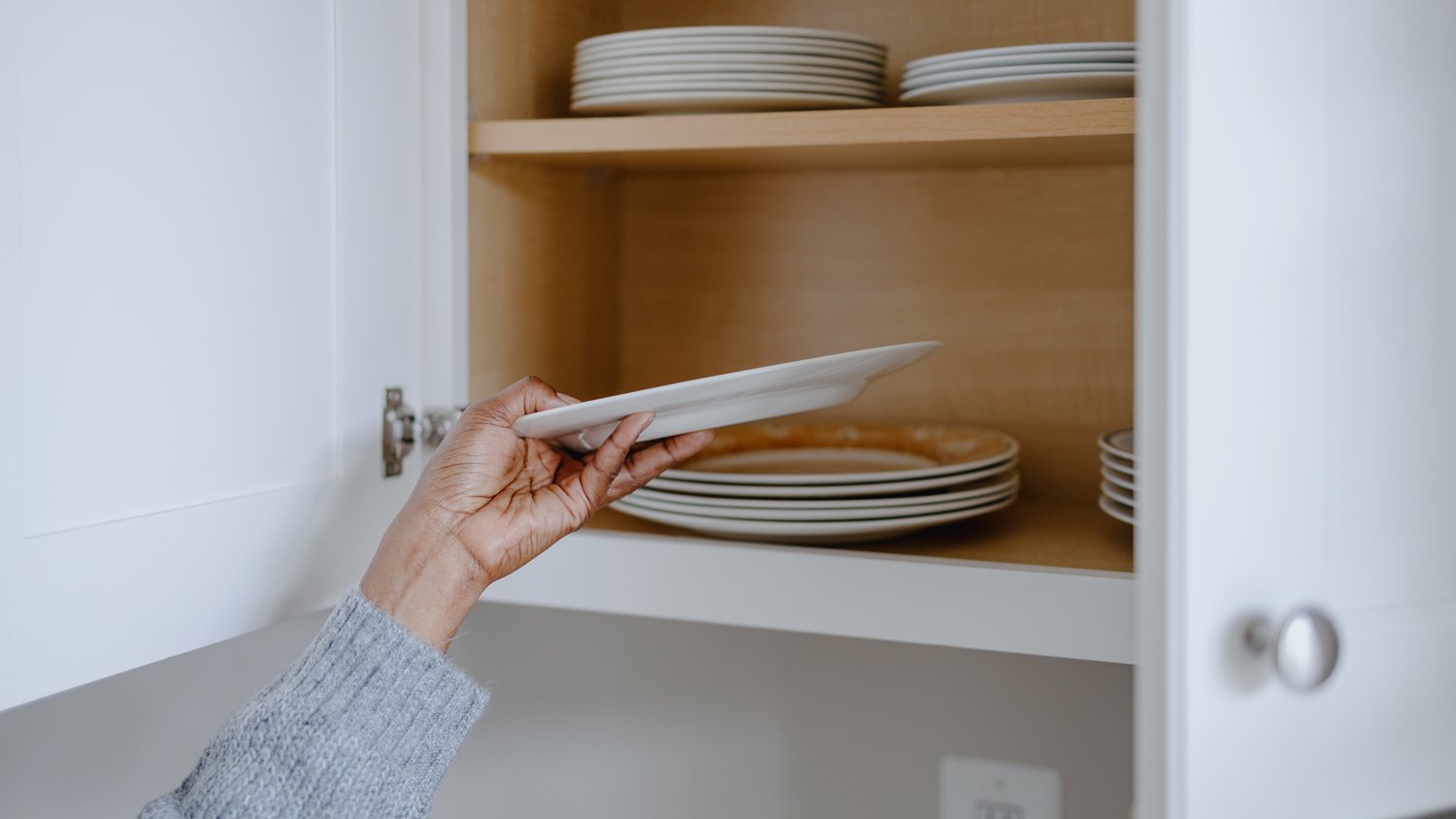 Woman Grabs a Plate From Kitchen Cabine