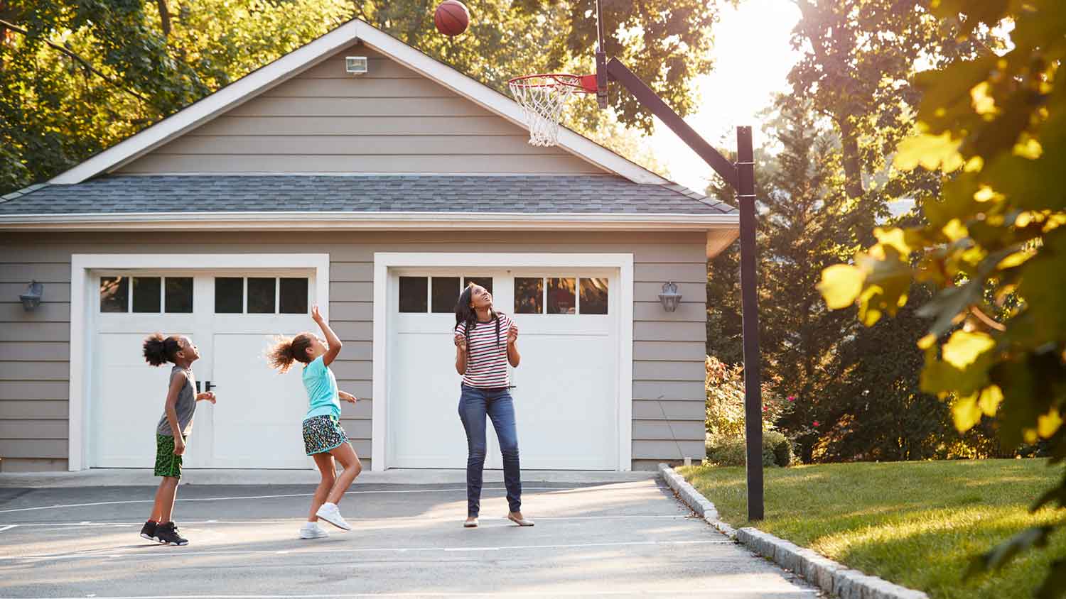 Mother and children playing basketball in the driveway