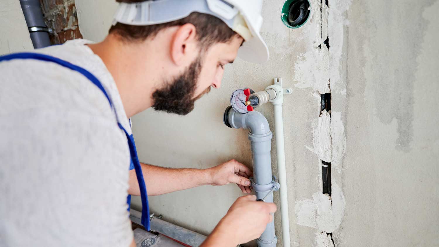 A plumber attaching a clamp to a pipe