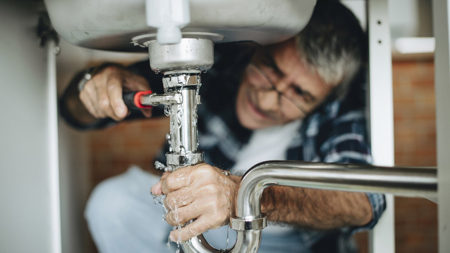 Plumber fixing a broken kitchen sink