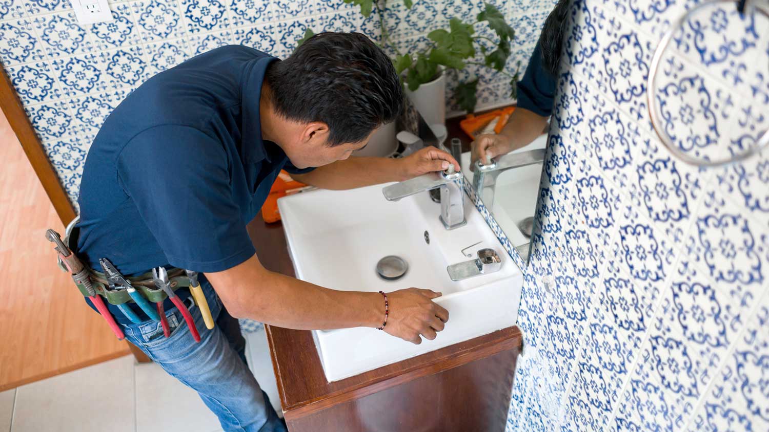 Plumber fixing bathroom faucet leak  