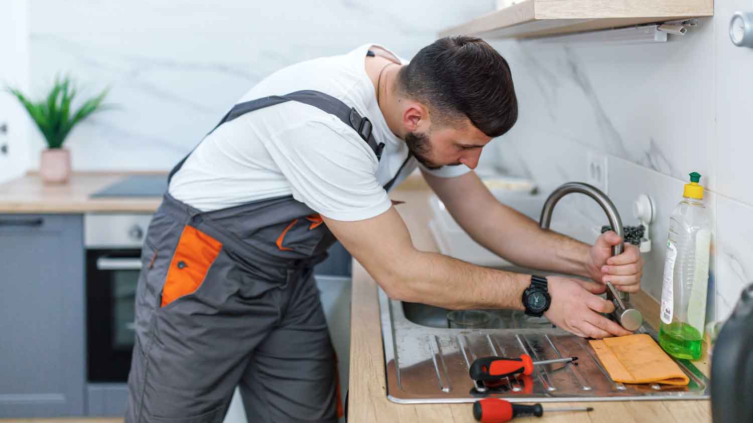 Plumber fixing kitchen faucet leak