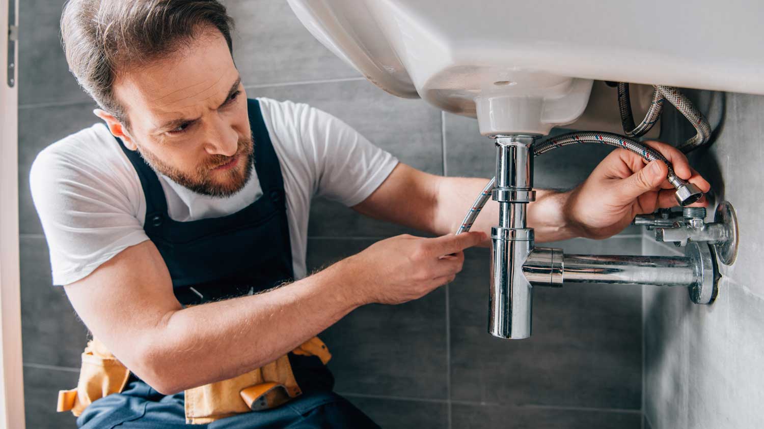 A plumber fixing a sink pipes issue