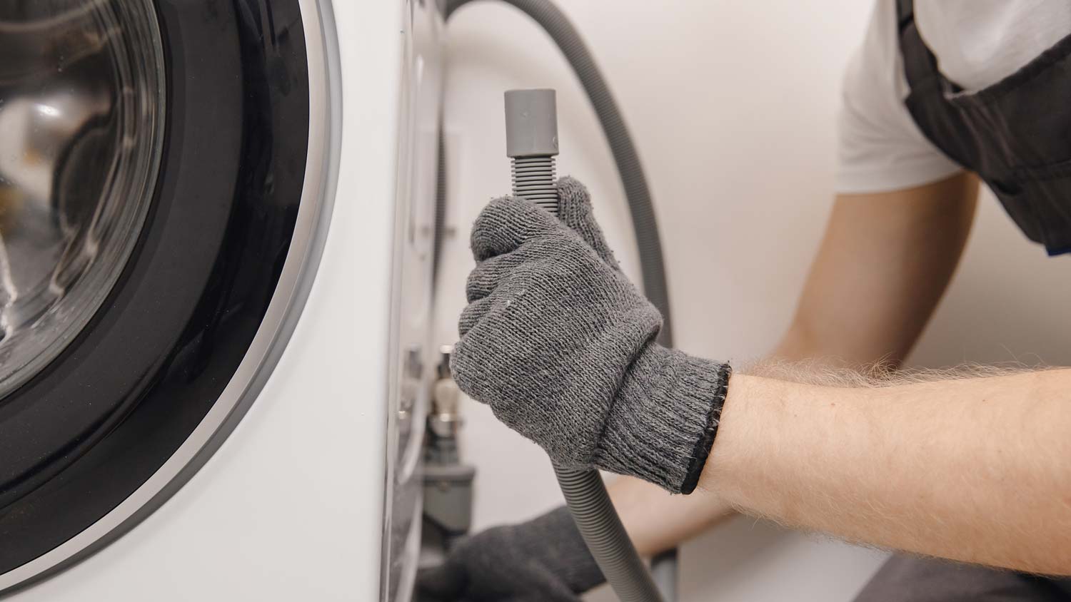 A plumber fixing a washer drain pipe