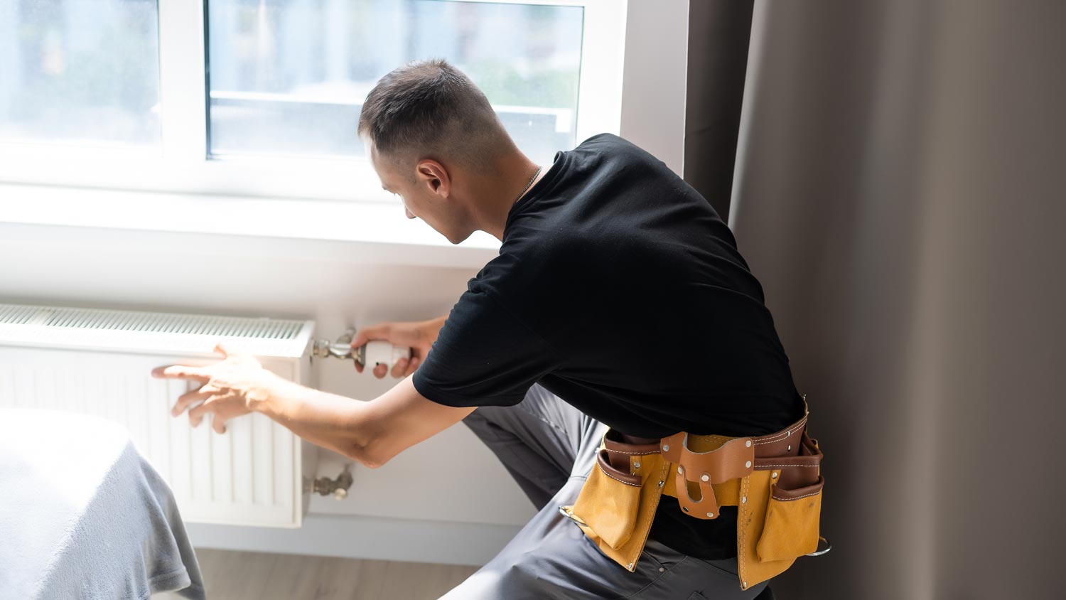 A plumber inspecting a radiator