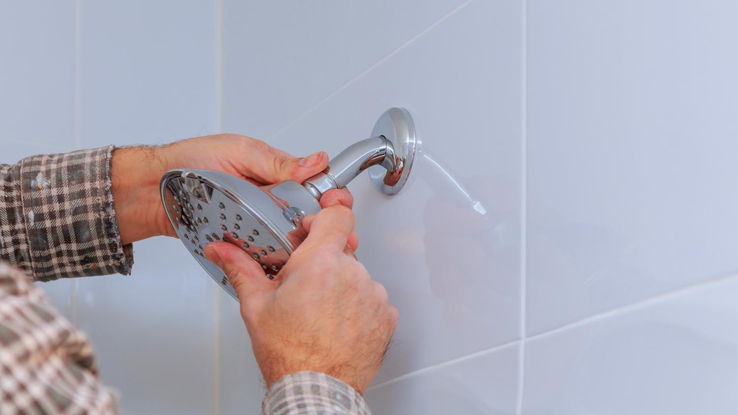 A plumber inspecting a shower head for leaks