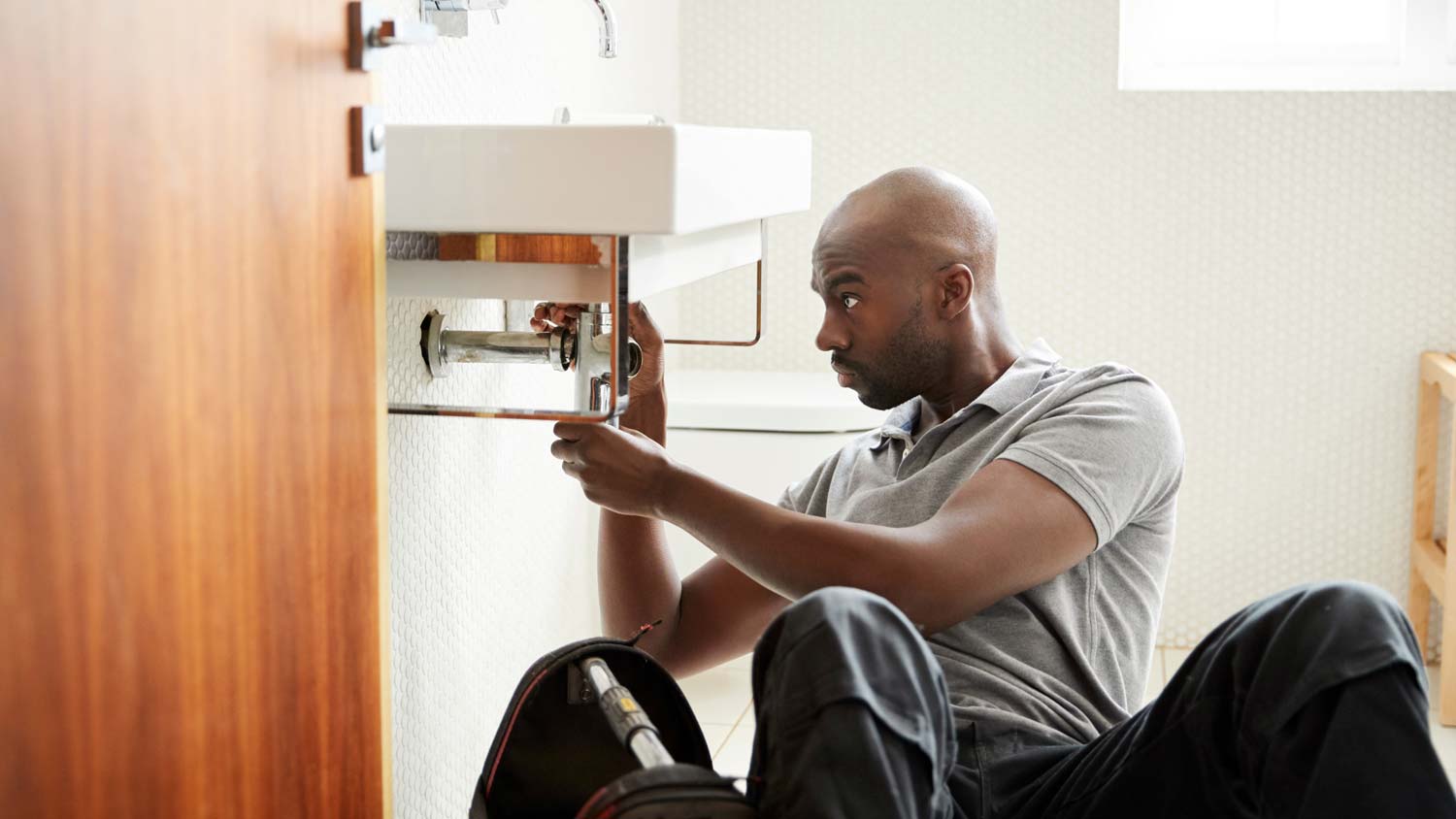 A plumber installing a small sink