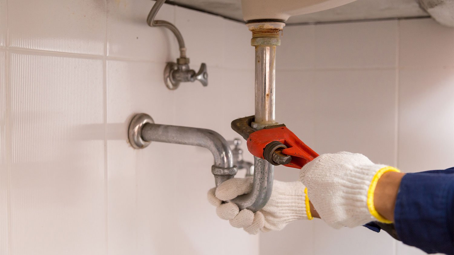 Plumber hand removing p trap from sink