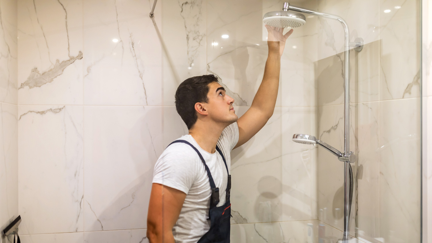 A plumber replacing the shower head in a bathroom