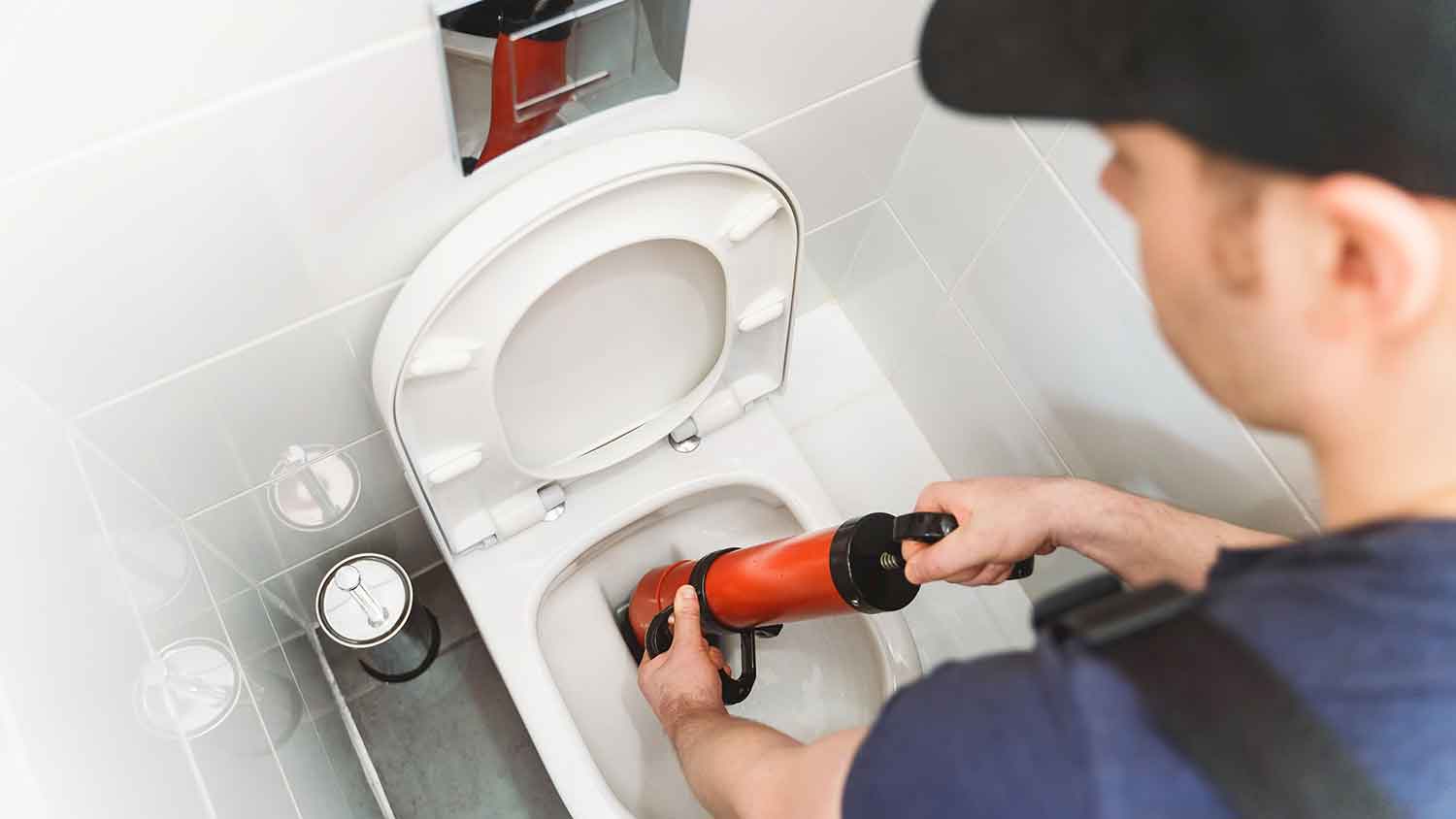 Plumber using force pump cleaner to unclog toilet