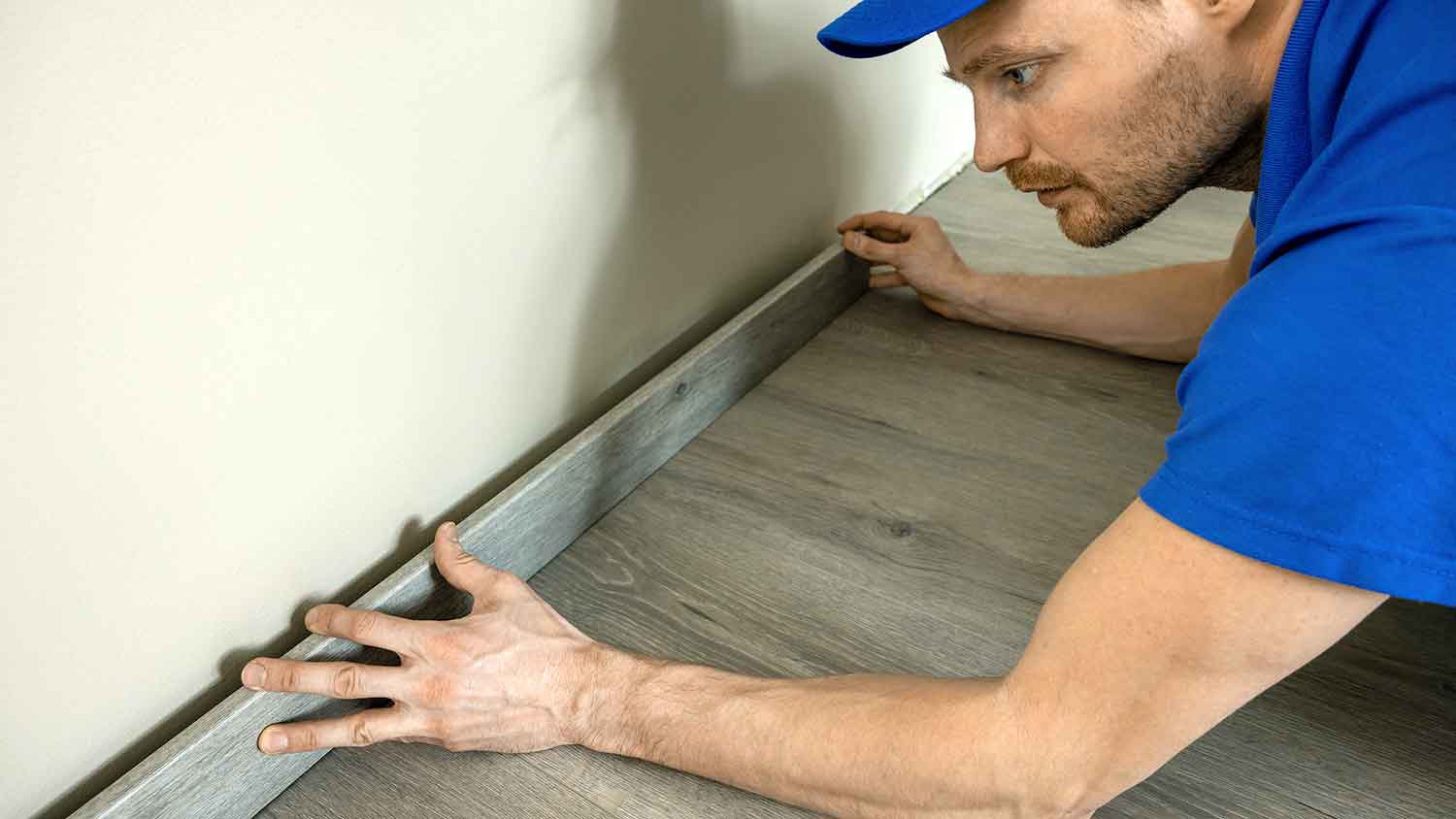 Worker installing polystyrene baseboard in the basement