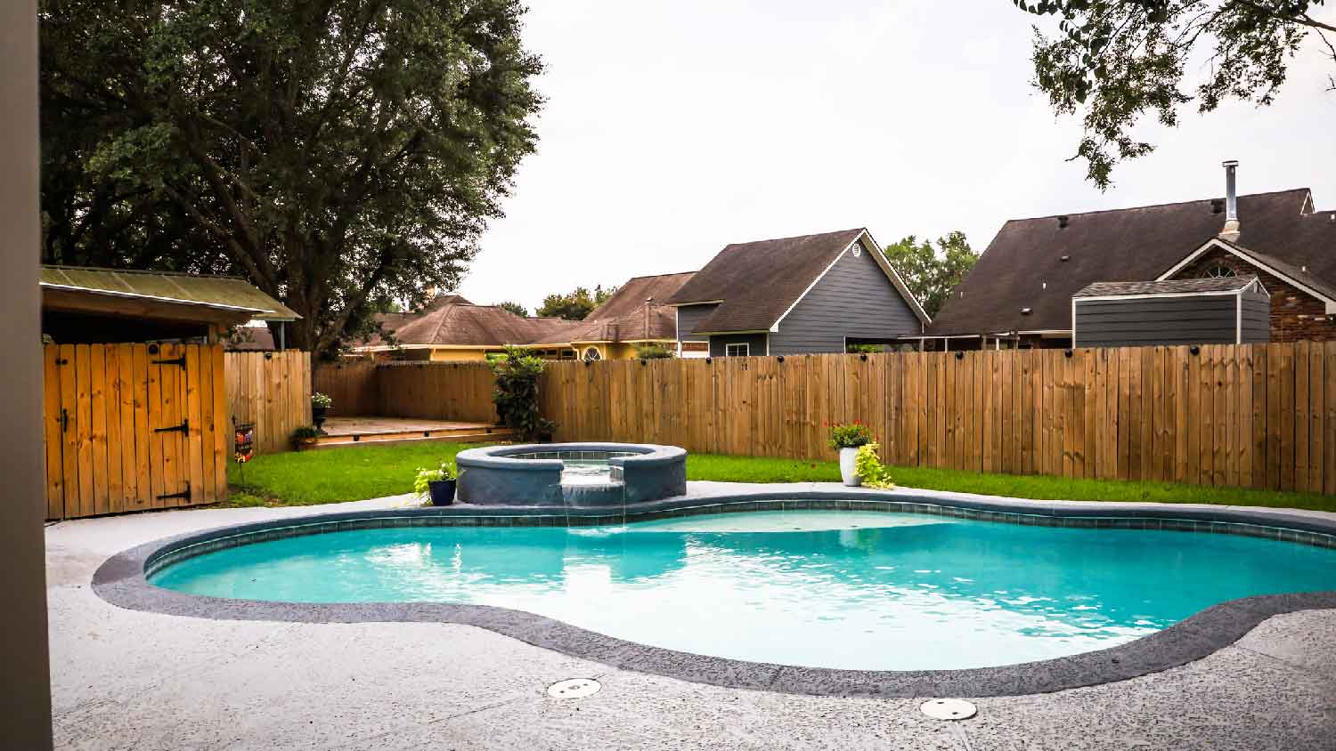 A pool in a backyard surrounded by a wooden fence