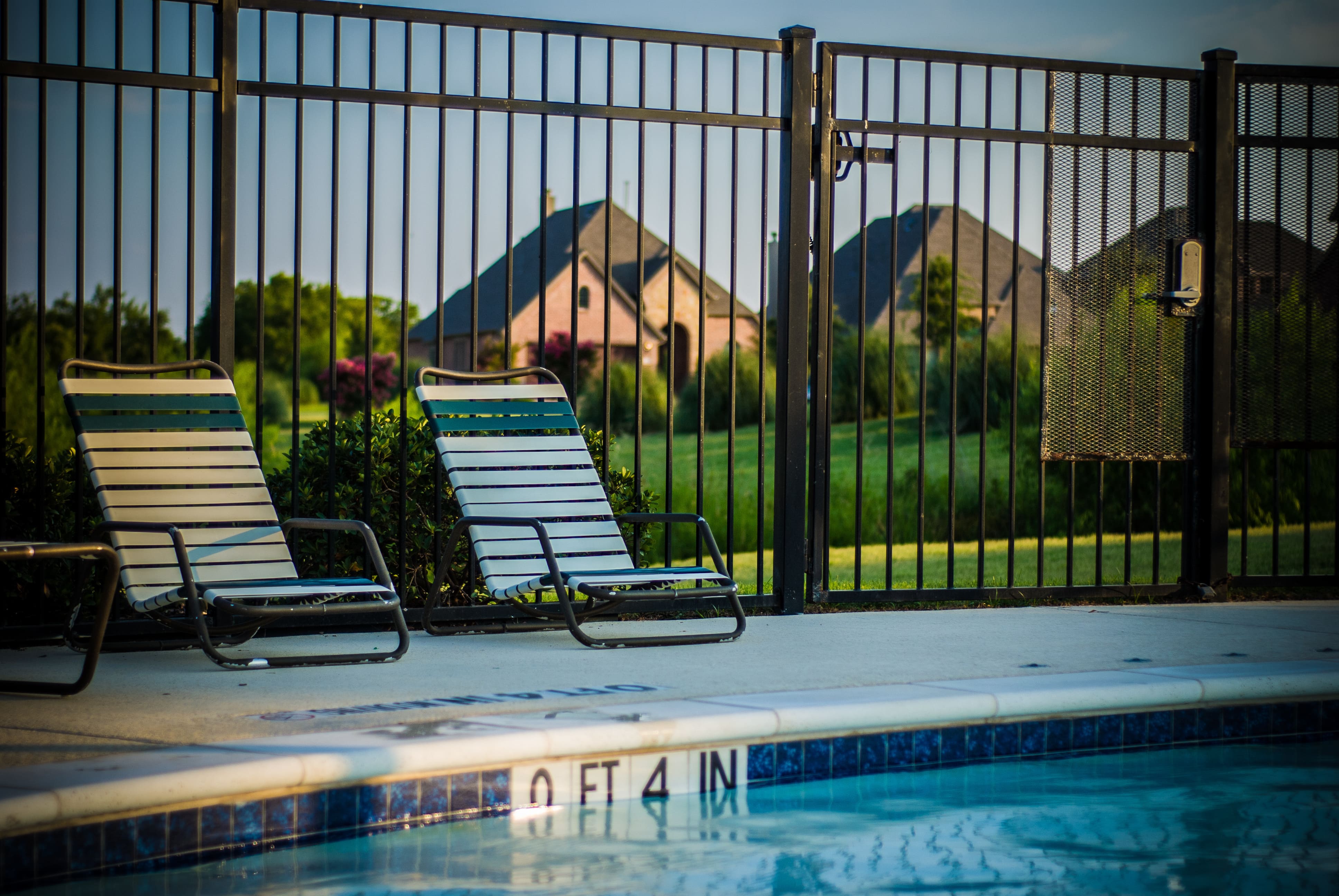 An inground pool enclosed by a black aluminum fence 