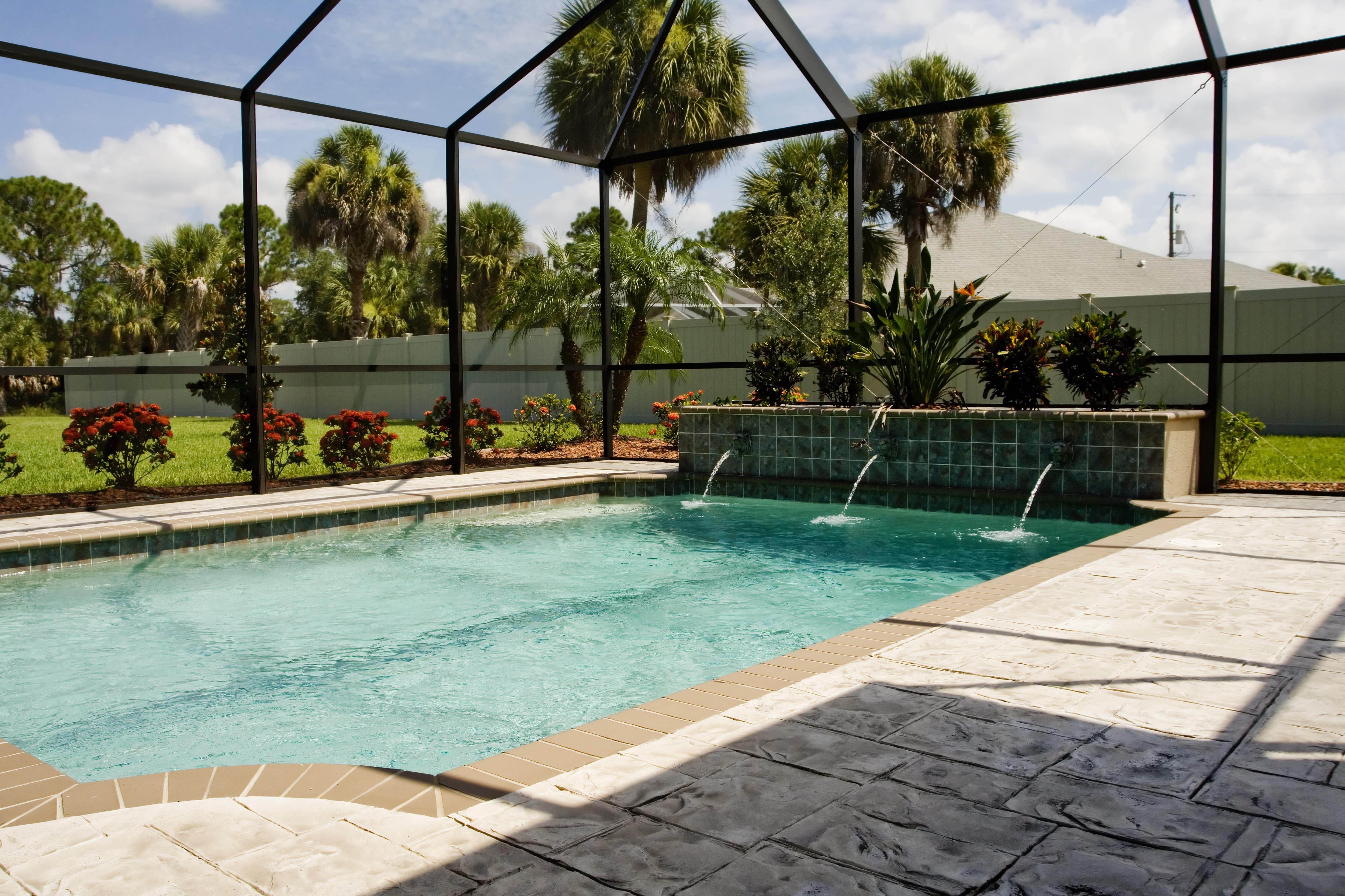 An inground pool in a screened in backyard area