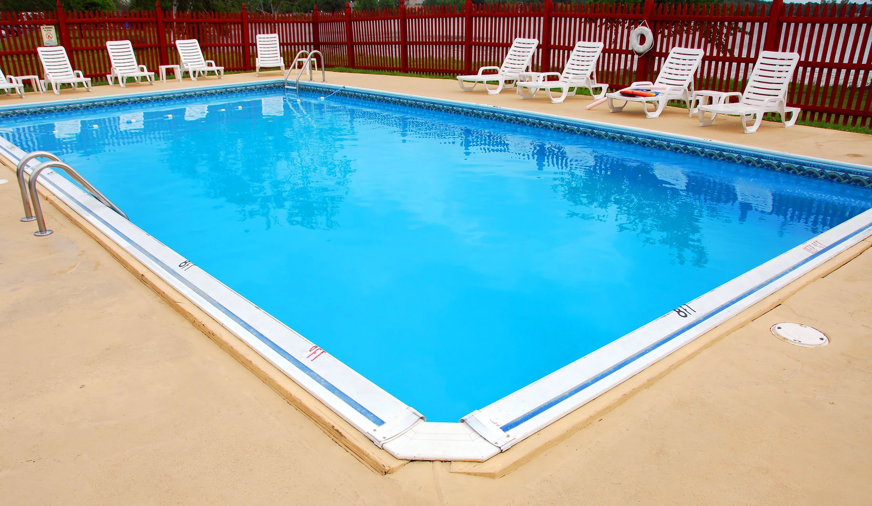 An inground pool with a bright red painted fence around it