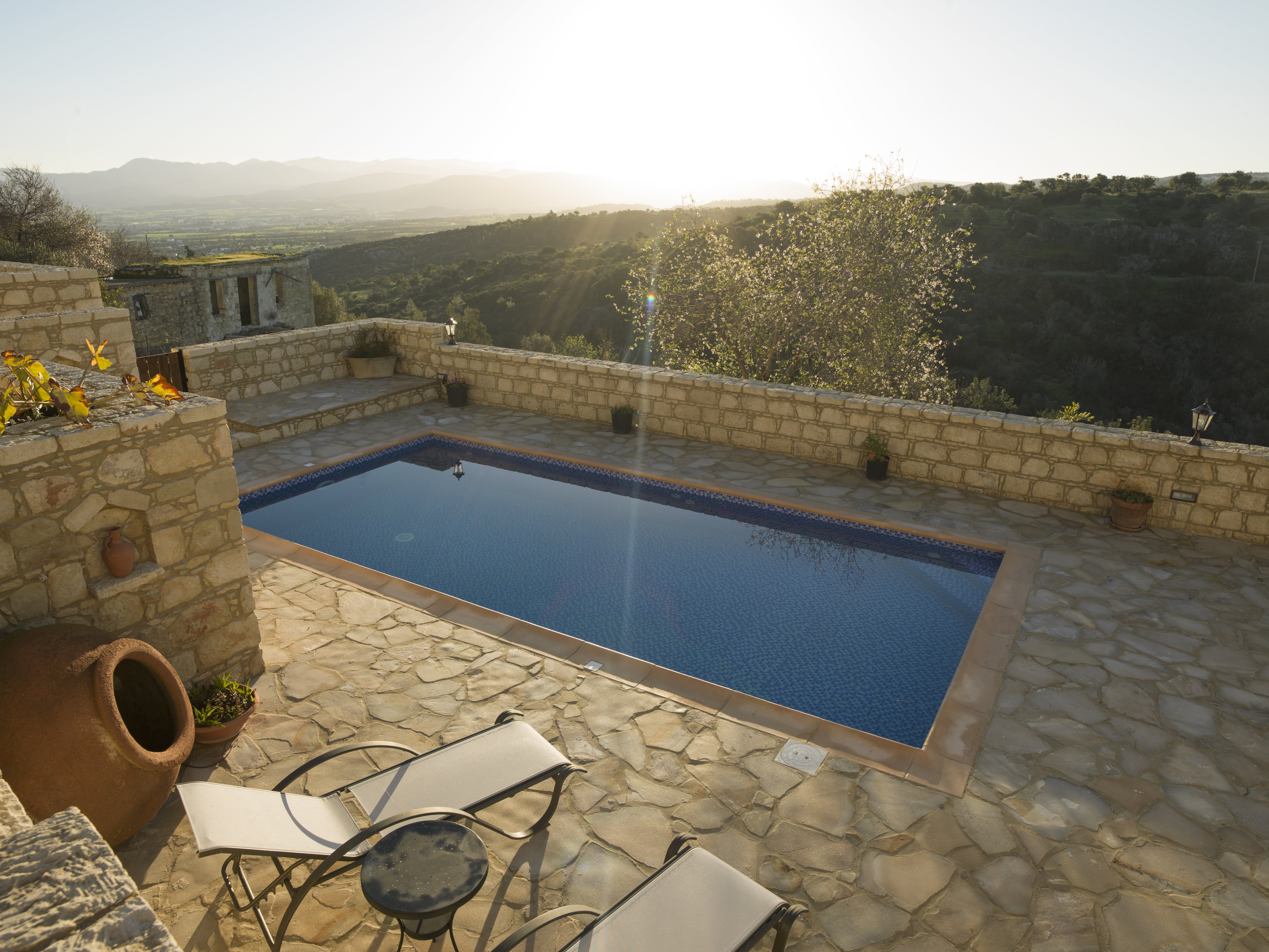 Sunrise near an inground pool that is surrounded by a stone wall