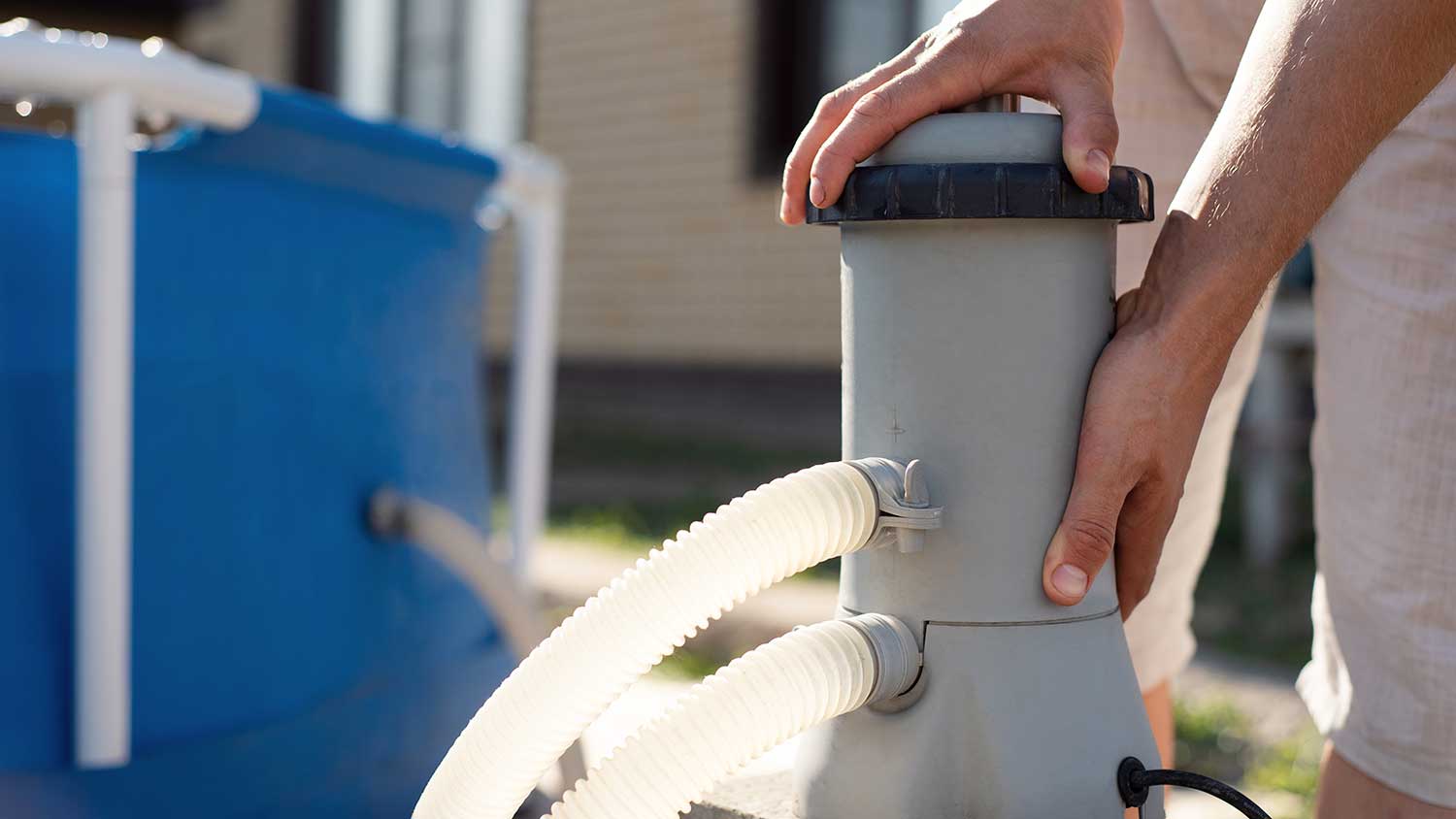 Man opening swimming pool filter for maintenance routine