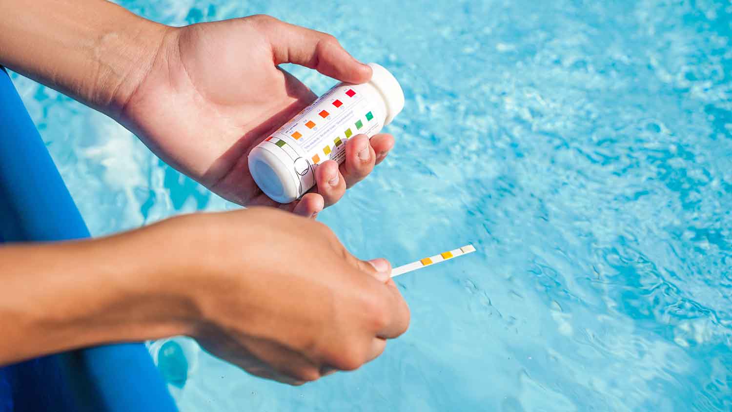 Person testing PH levels in a swimming pool 