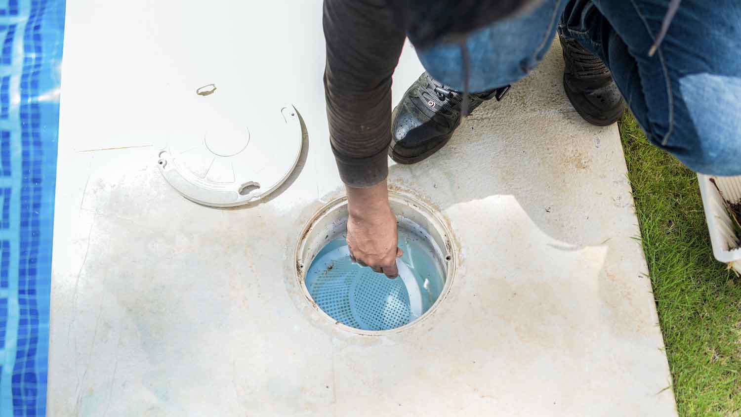 Handyperson cleaning swimming pool skimmer basket