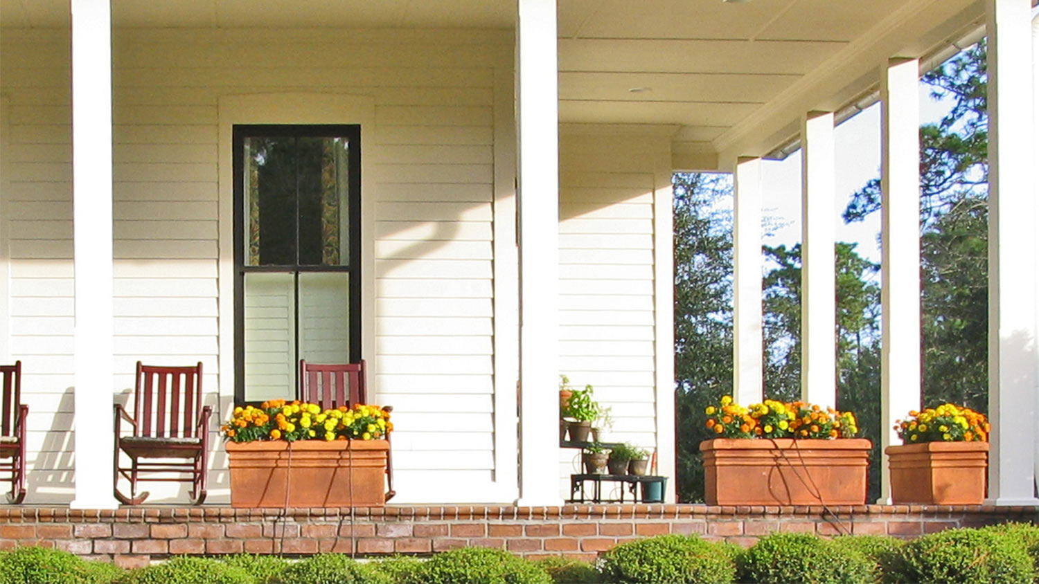 A wrap-around porch with colorful planter boxes