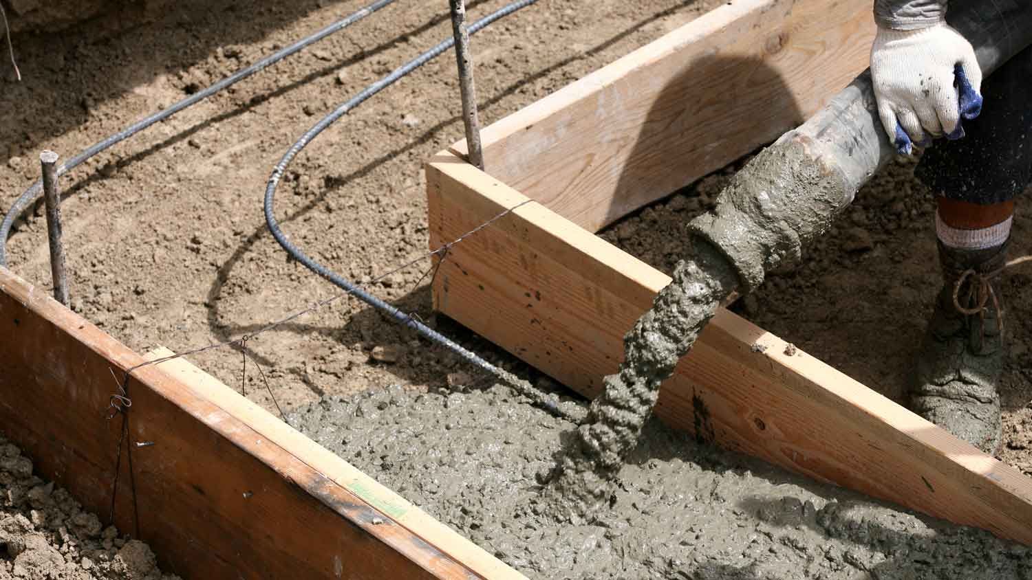 Close-up of pouring concrete between batten boards to form a house’s foundation