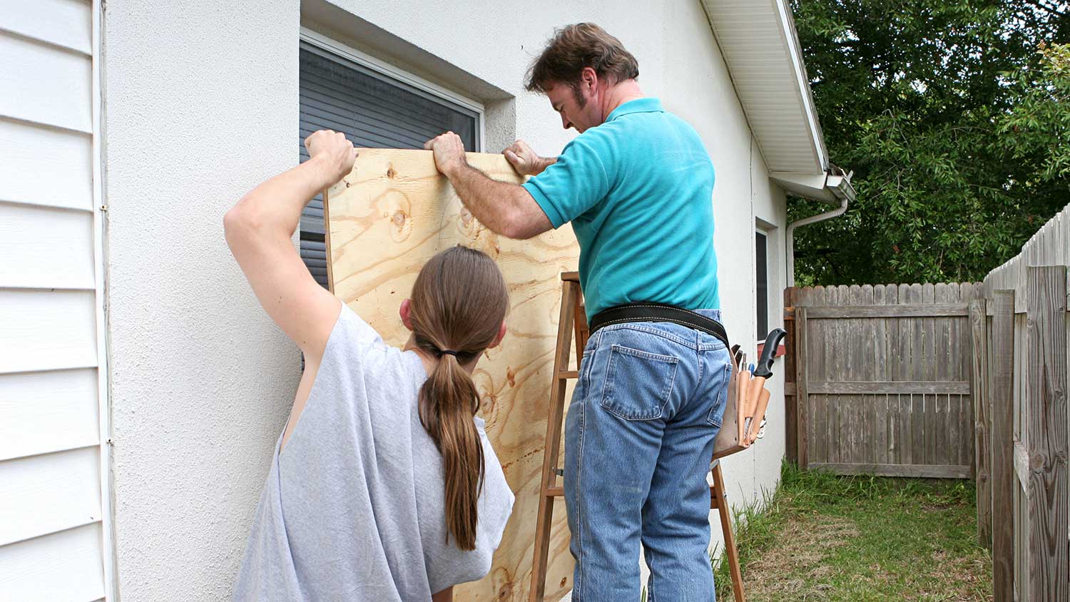 Men boarding up windows for hurricane protection