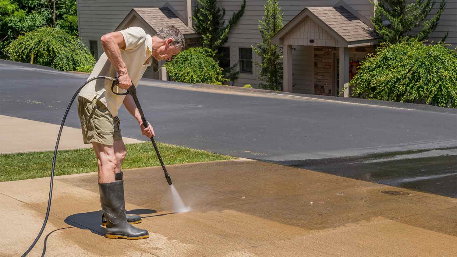 man pressure spraying concrete driveway