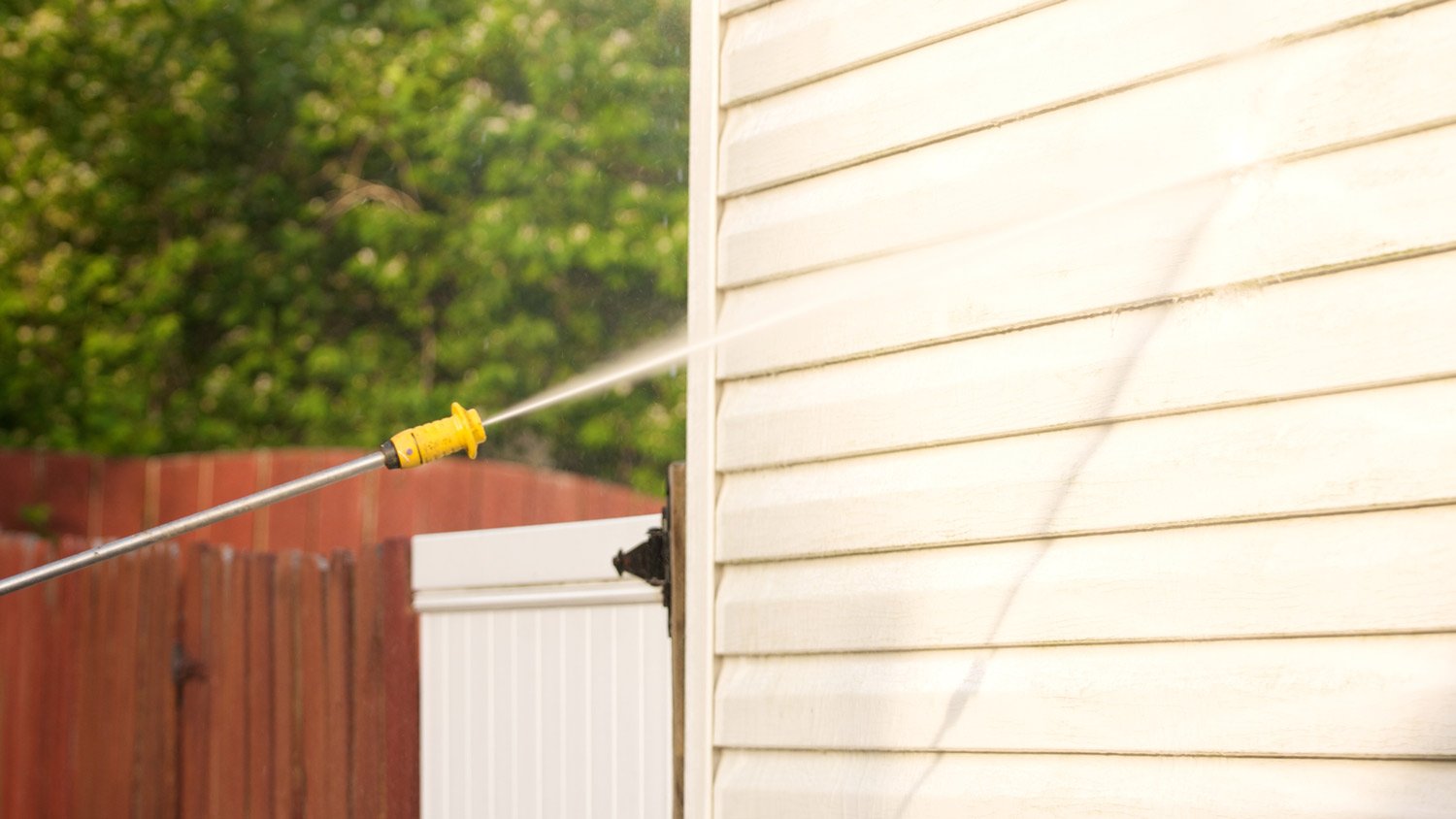 Close-up of a pressure washer washing a house’s wall