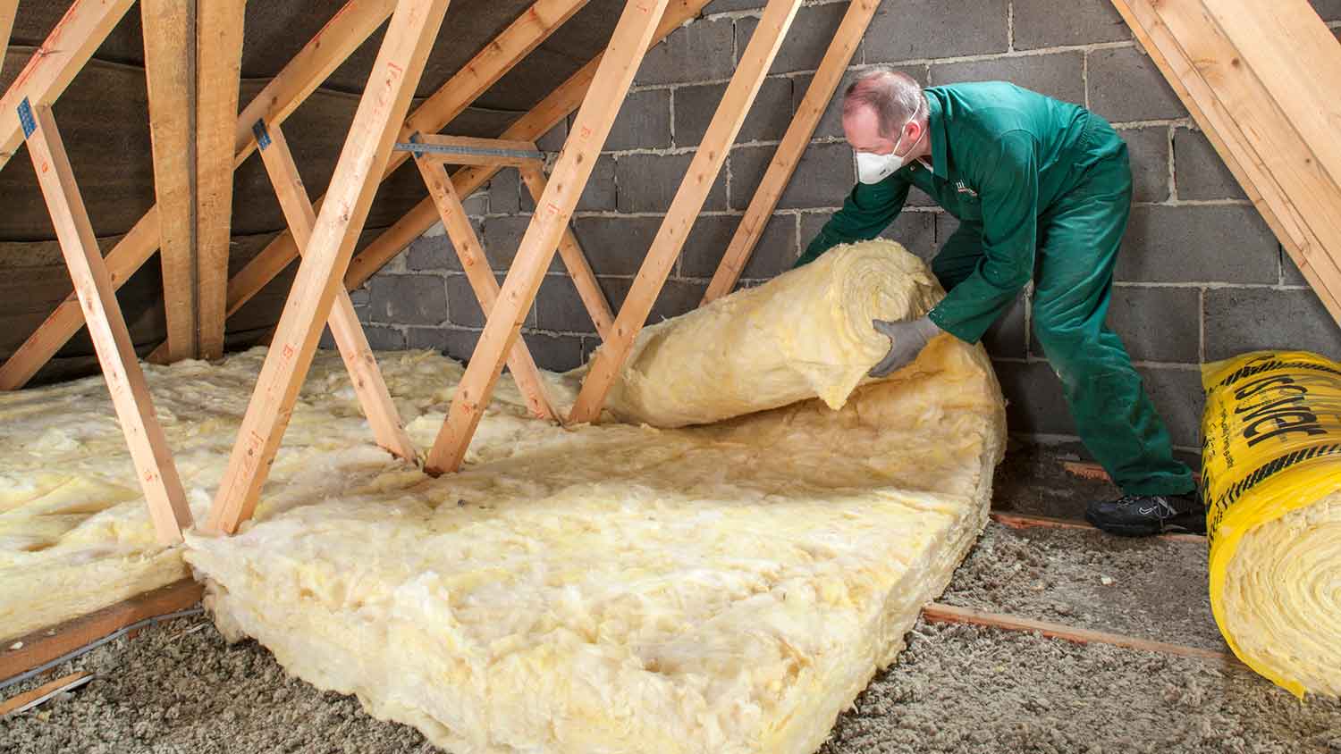 Insulation professional installing fiberglass insulation in the attic