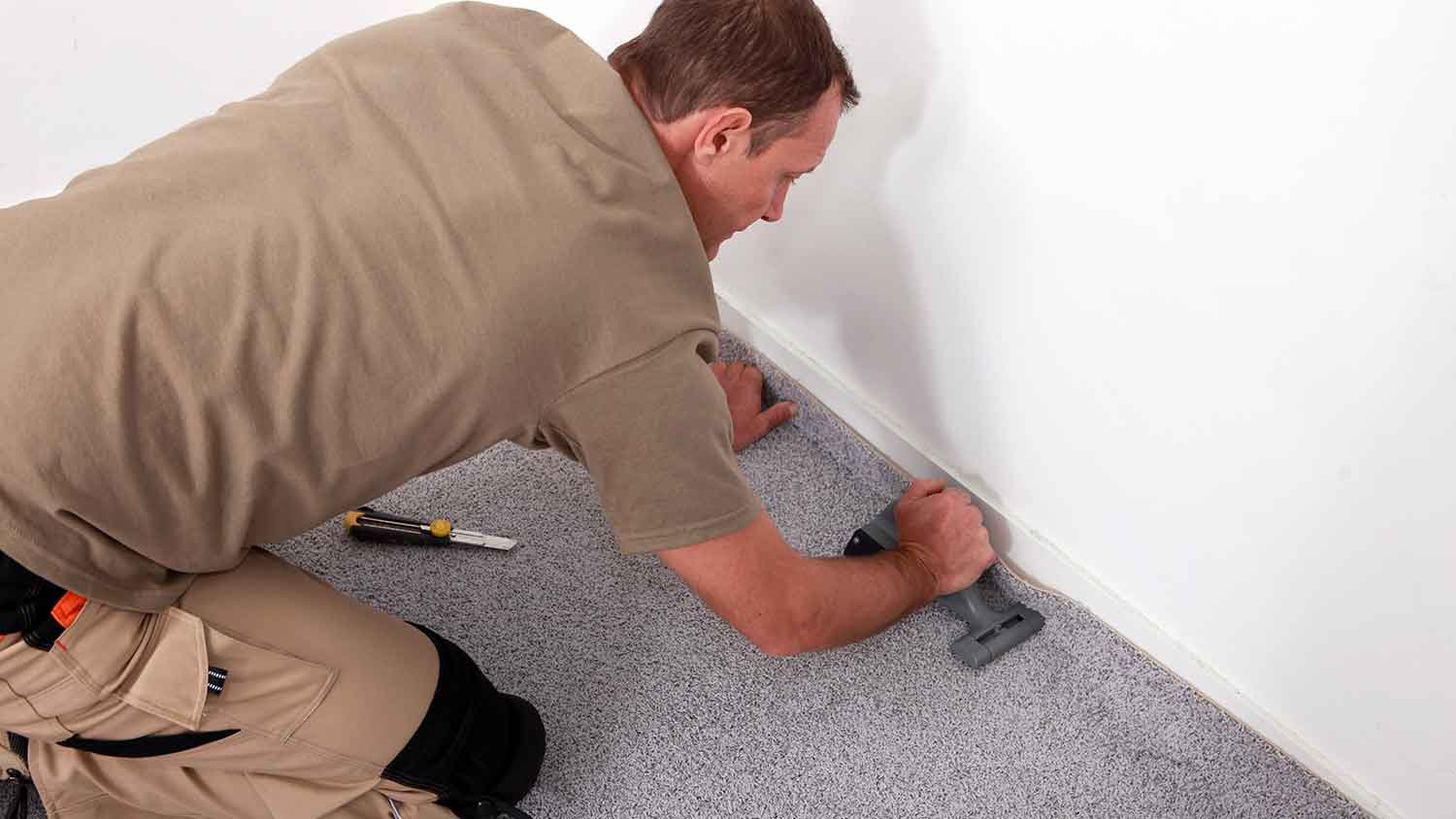 Worker installing carpet in the room