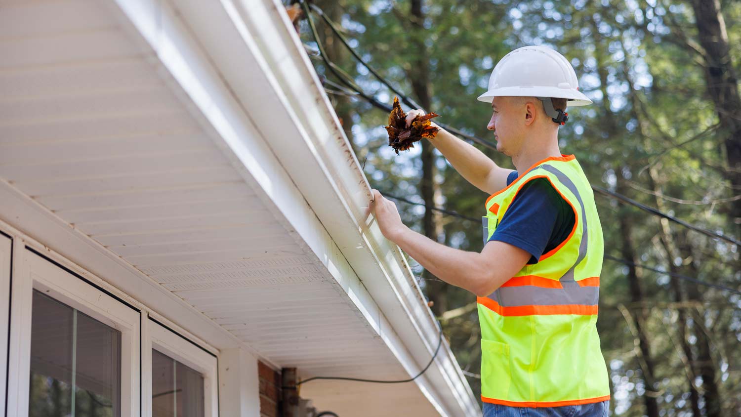 professional worker cleaning out gutters