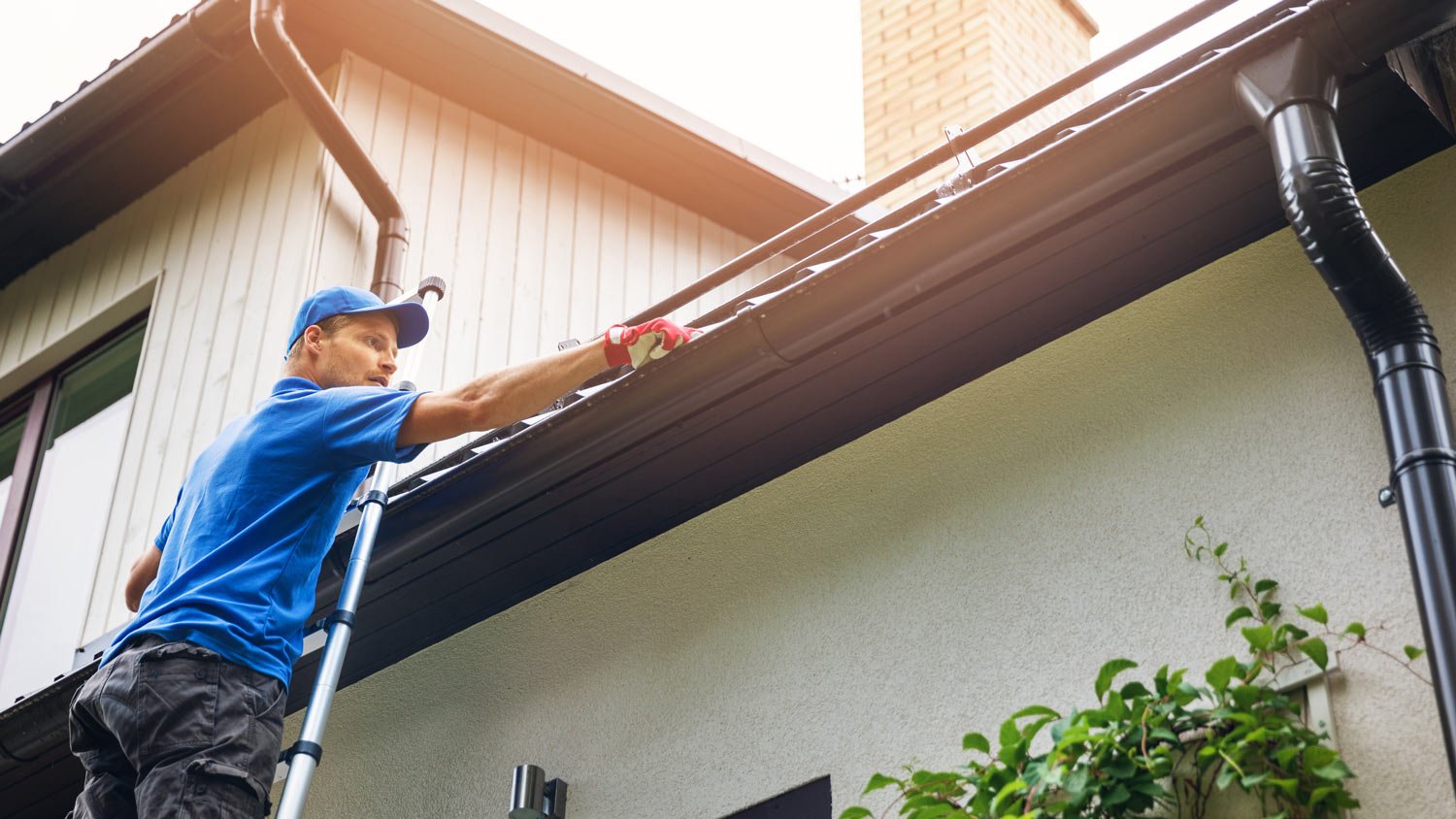 A professional cleaning the gutter of a roof