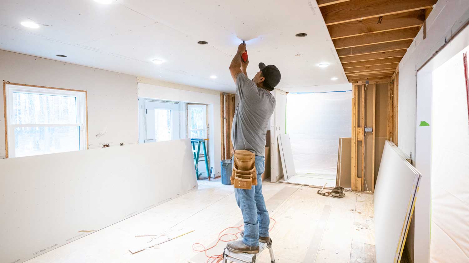 Drywall installer attaching drywall sheet on the ceiling
