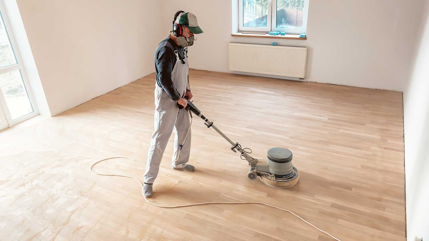 Harwood floor refinisher using machine to polish the floor