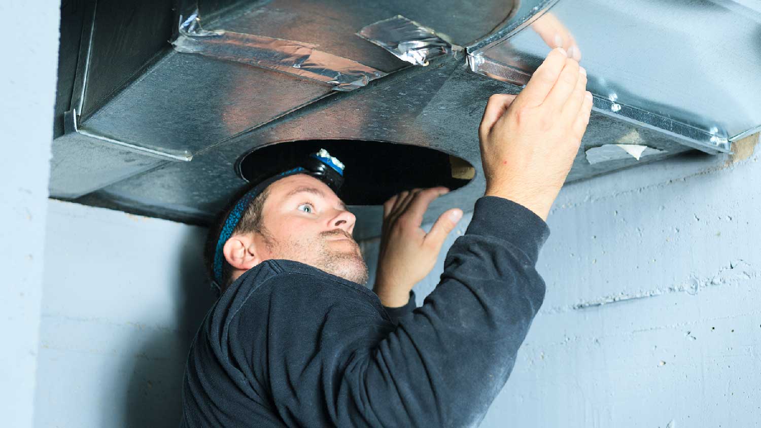 A professional inspecting ductwork