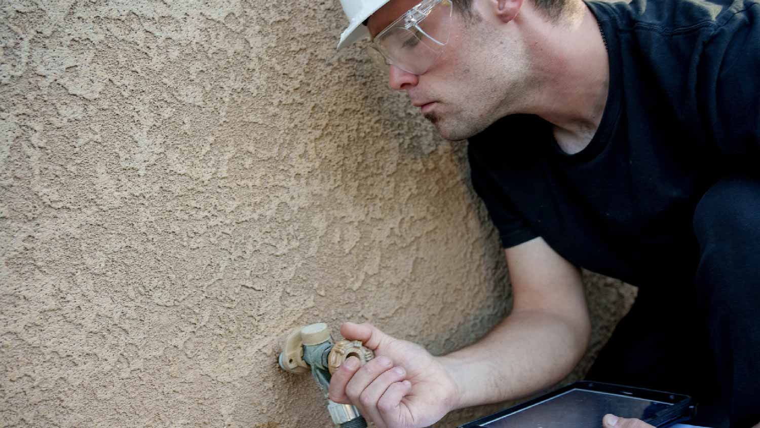 A professional inspecting an outside spigot