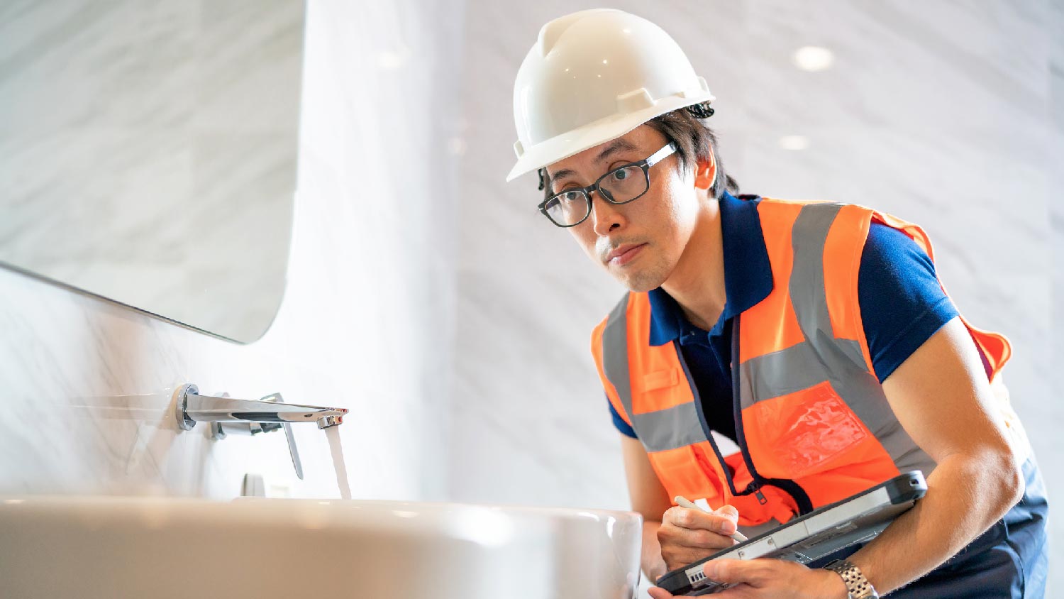 A professional inspecting a wall-mounted faucet