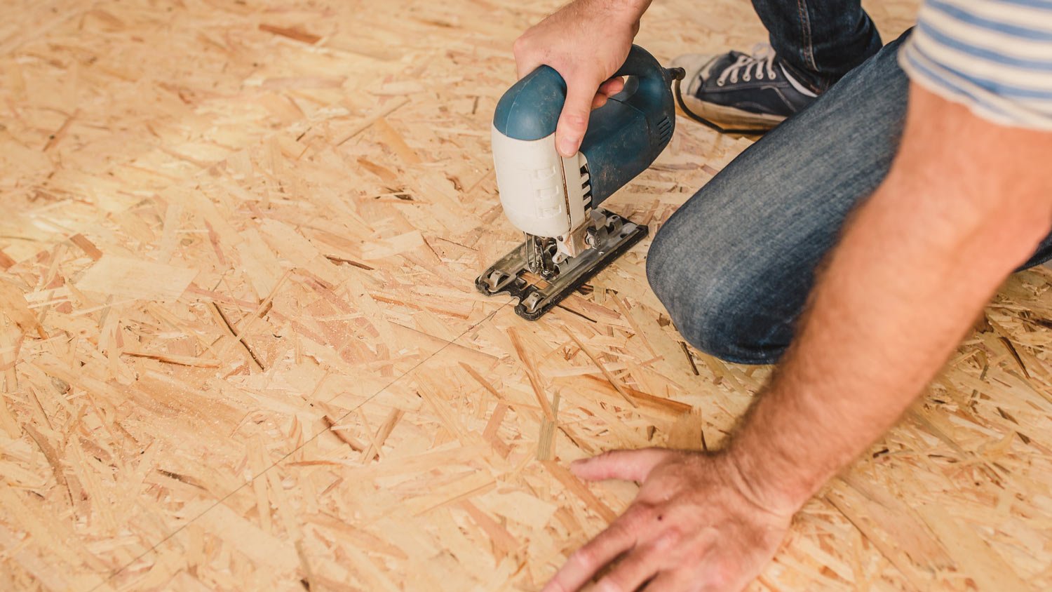 A professional installing a subfloor board