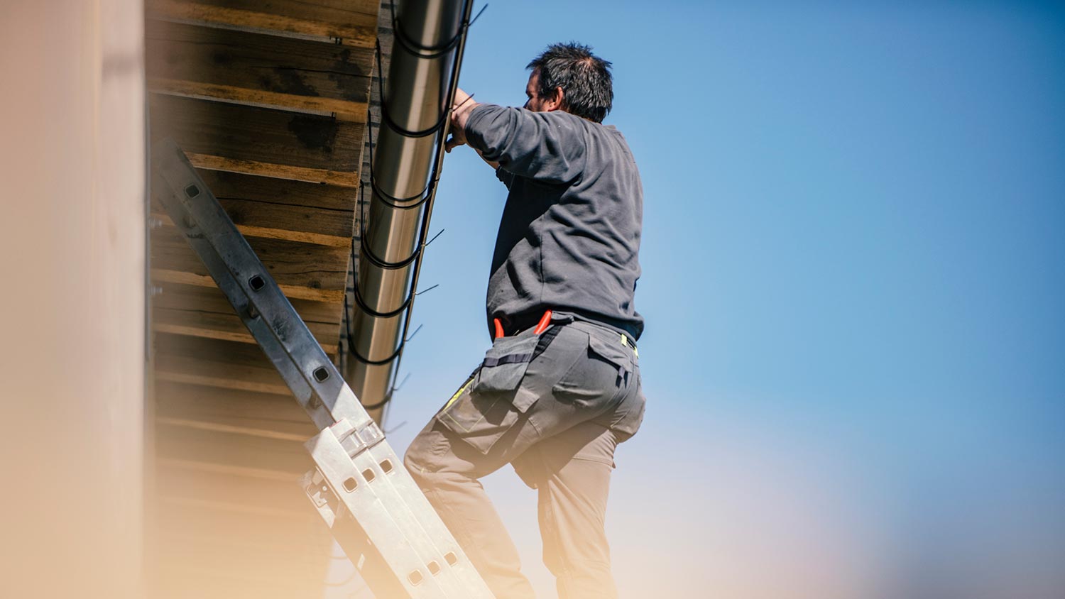 A professional installing gutters