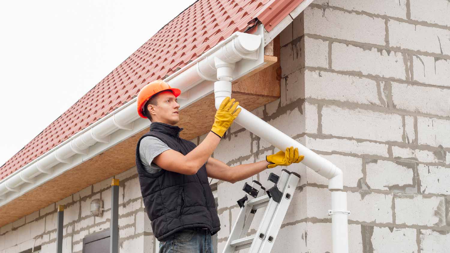 A professional installing a new downspout