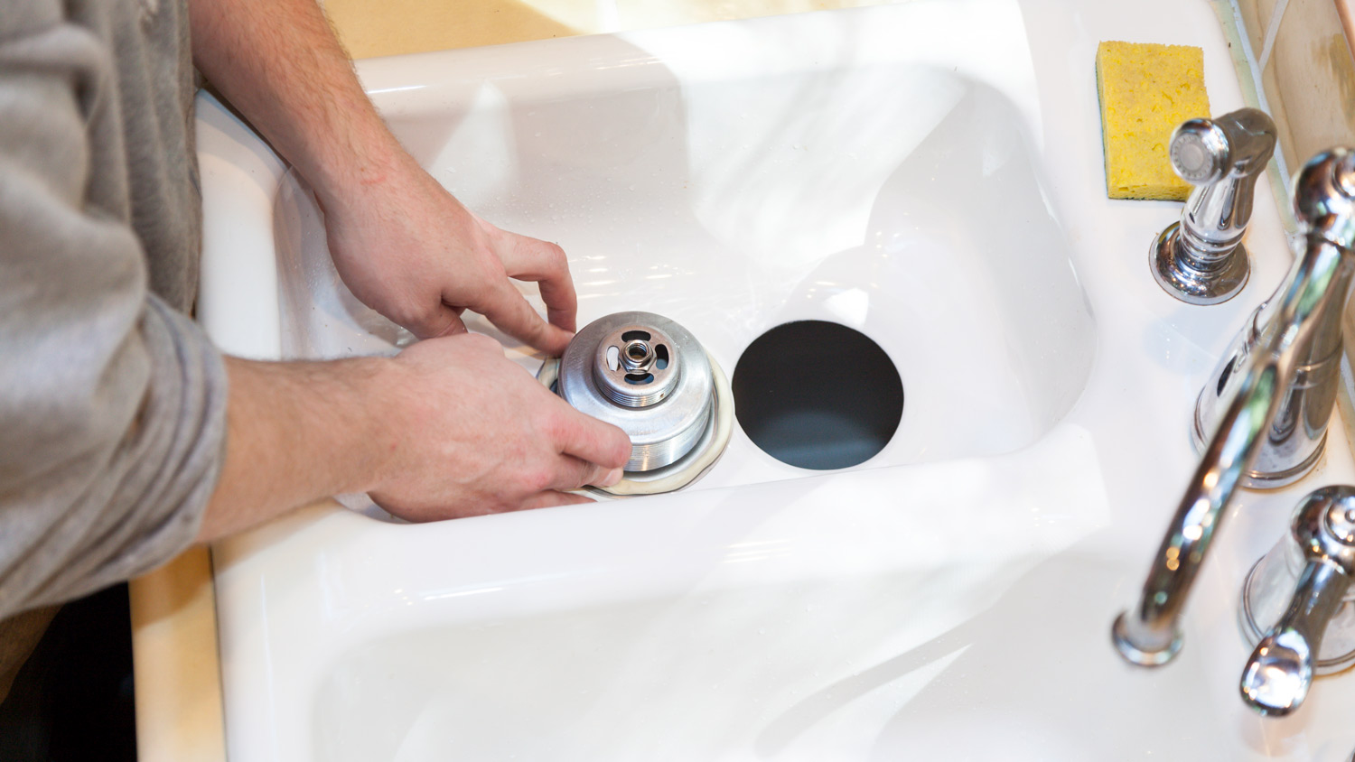 A professional installing a garbage disposal in a kitchen’s sink