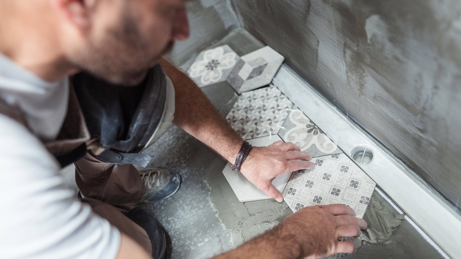 A professional laying new tiles on bathroom floor