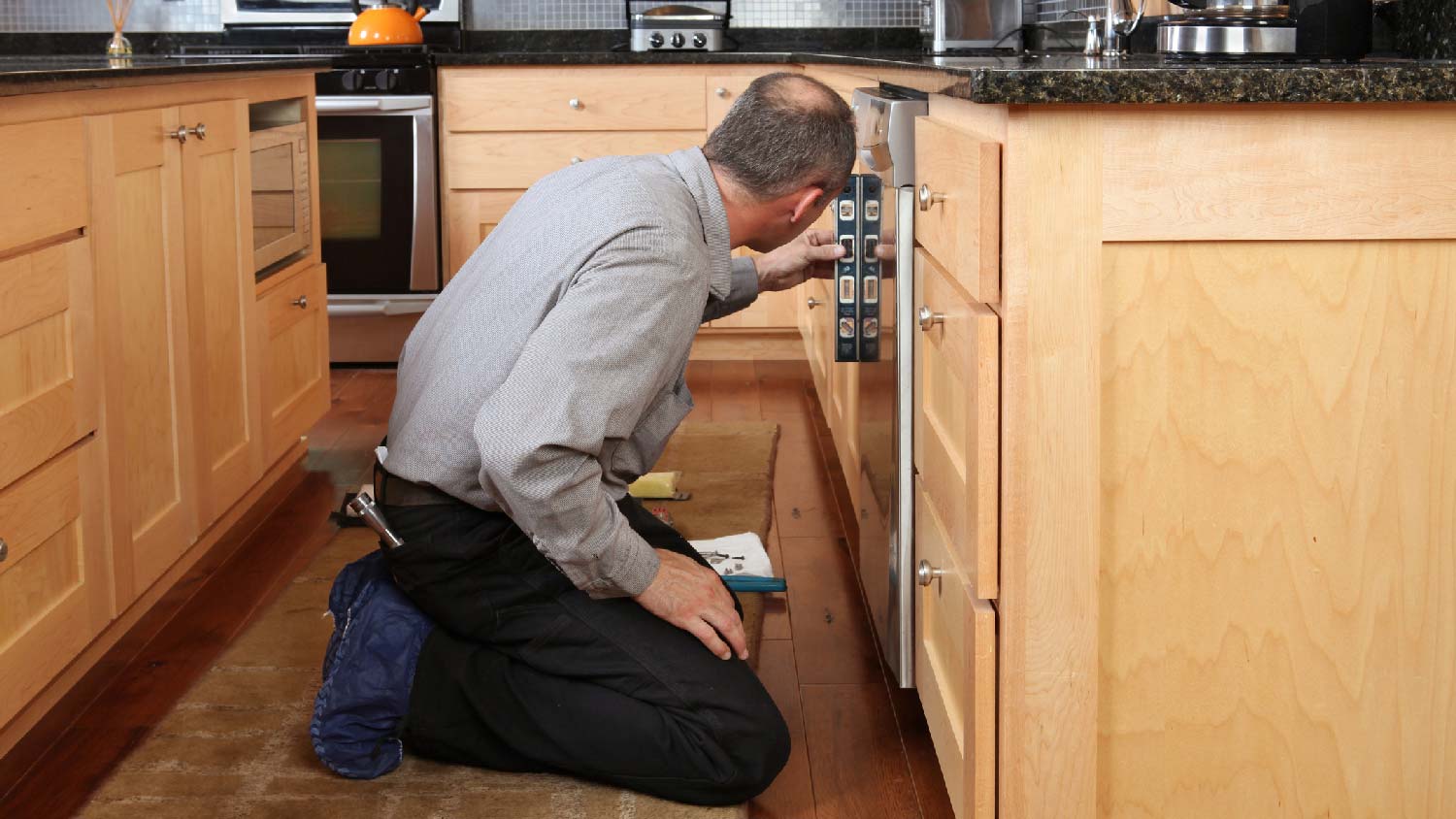 A professional levelling a dishwasher