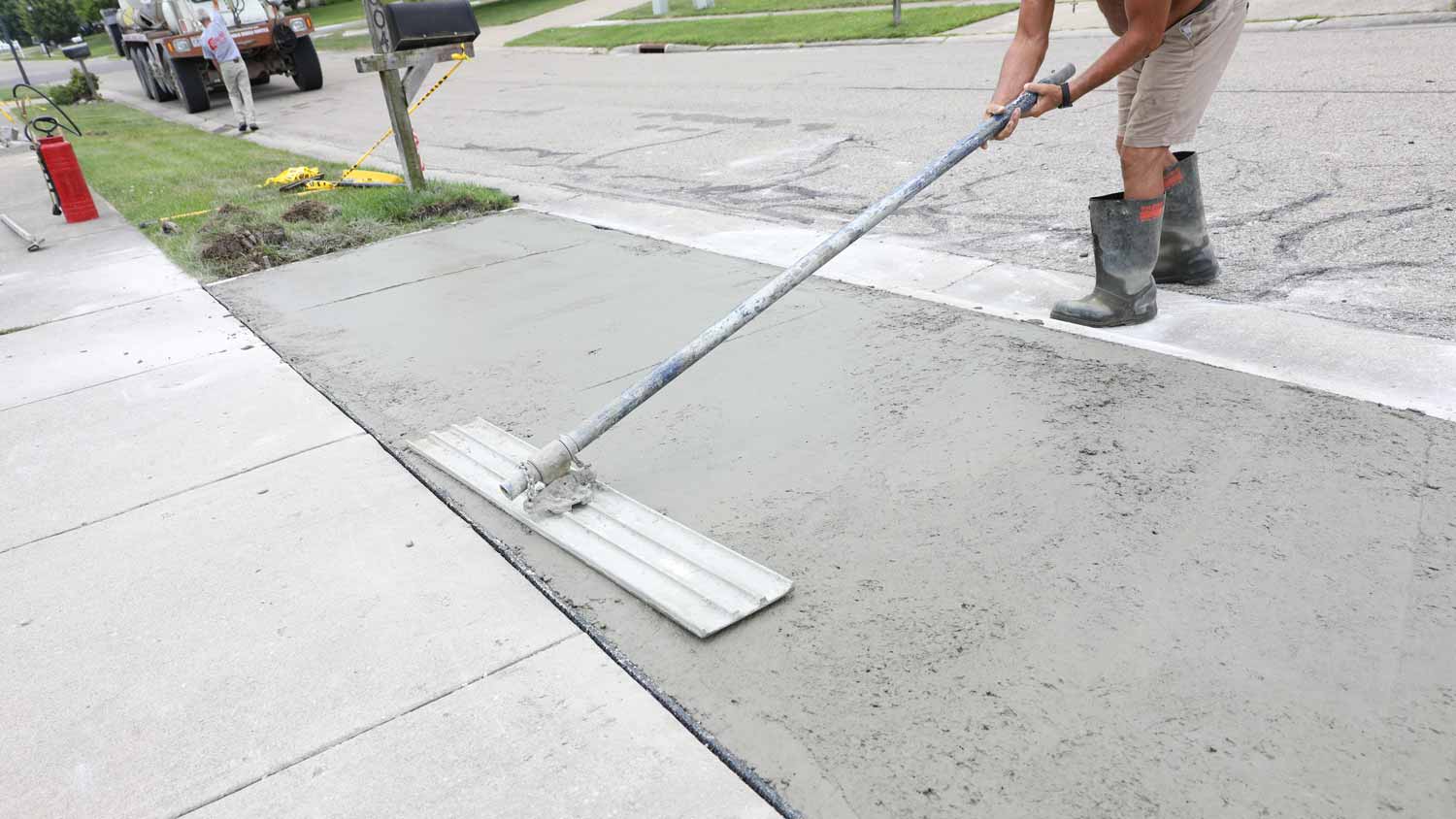 A professional levelling a driveway apron