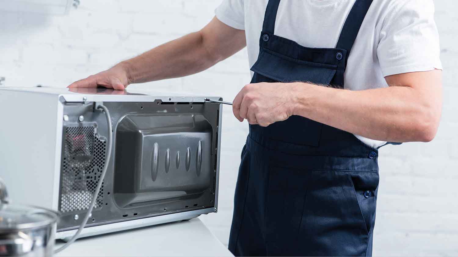 Technician repairing a microwave in the kitchen 