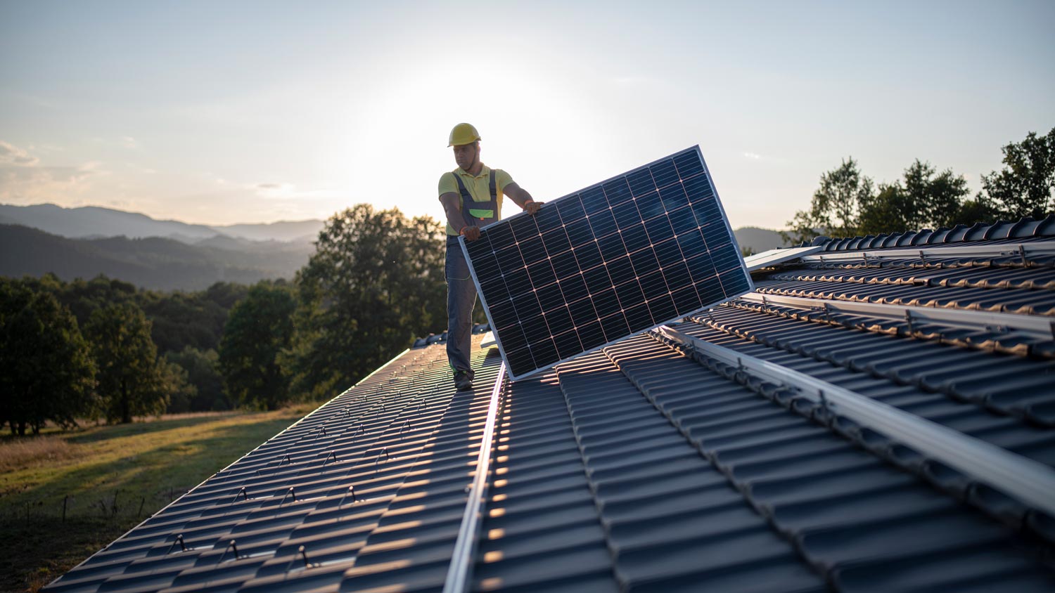 A professional placing a solar panel on the roof of a house